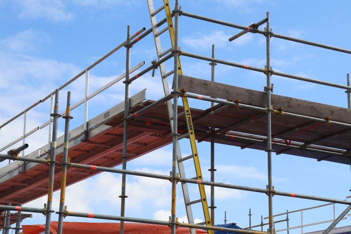 System scaffold with guardrails, timber decks and an access ladder against a blue sky