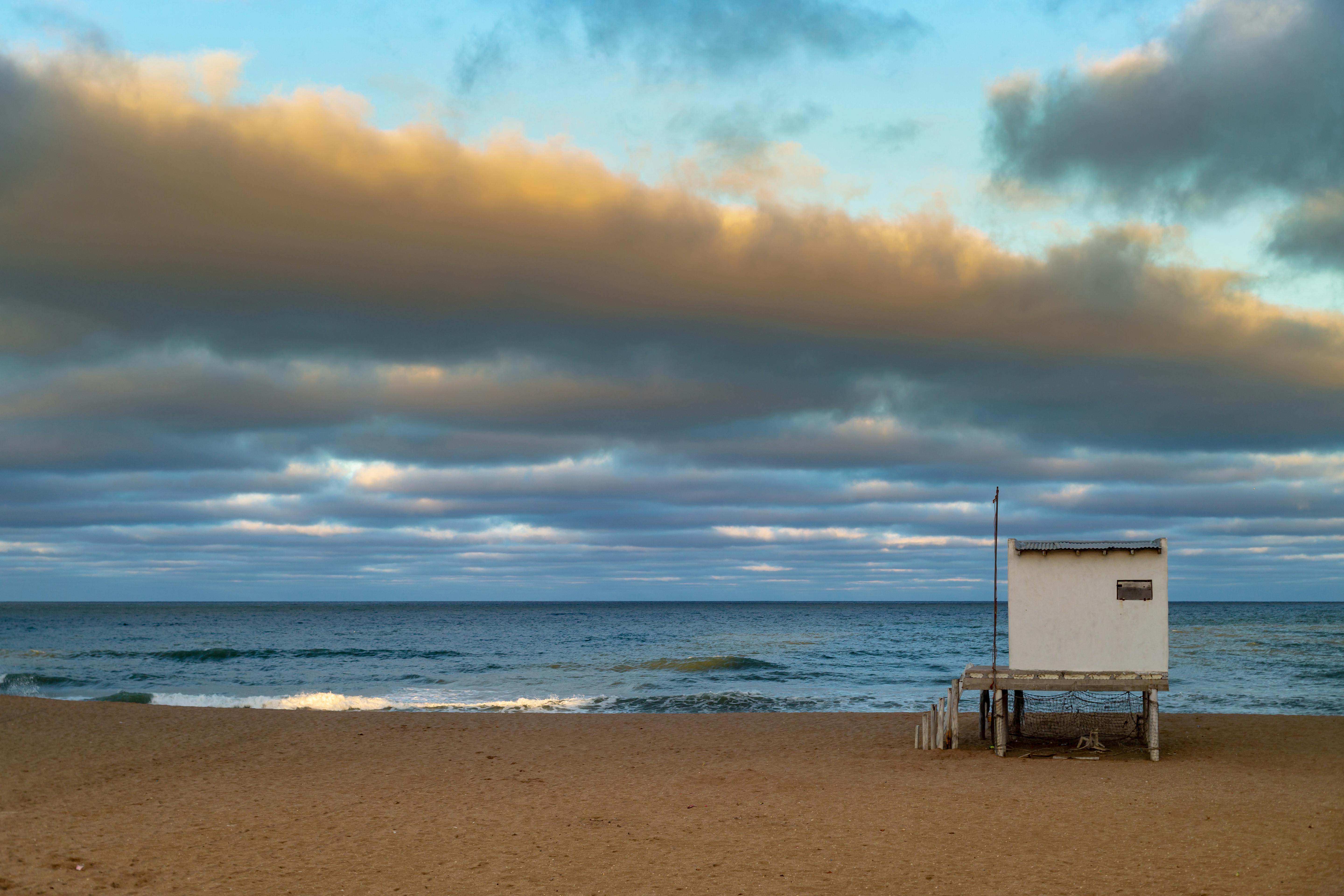 A serene beach view with a lifeguard hut and a beautiful sunset sky in Mar del Plata, Argentina.