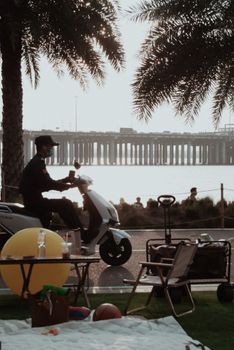 A person rides a scooter by the waterfront in Shenzhen park during sunset.