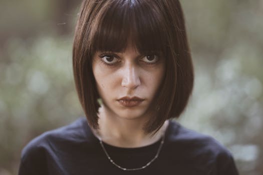 Close-up portrait of a serious woman with short dark hair and intense gaze, outdoors.
