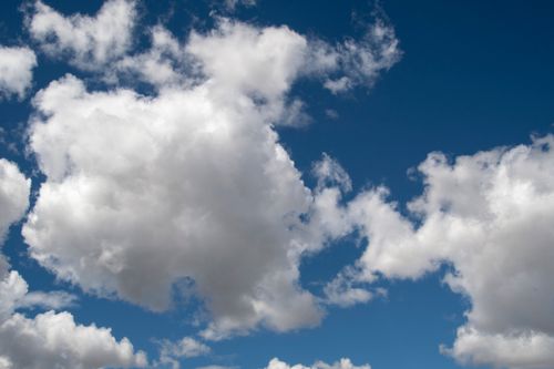 Free Bright blue sky filled with large, fluffy white clouds on a sunny day. Stock Photo