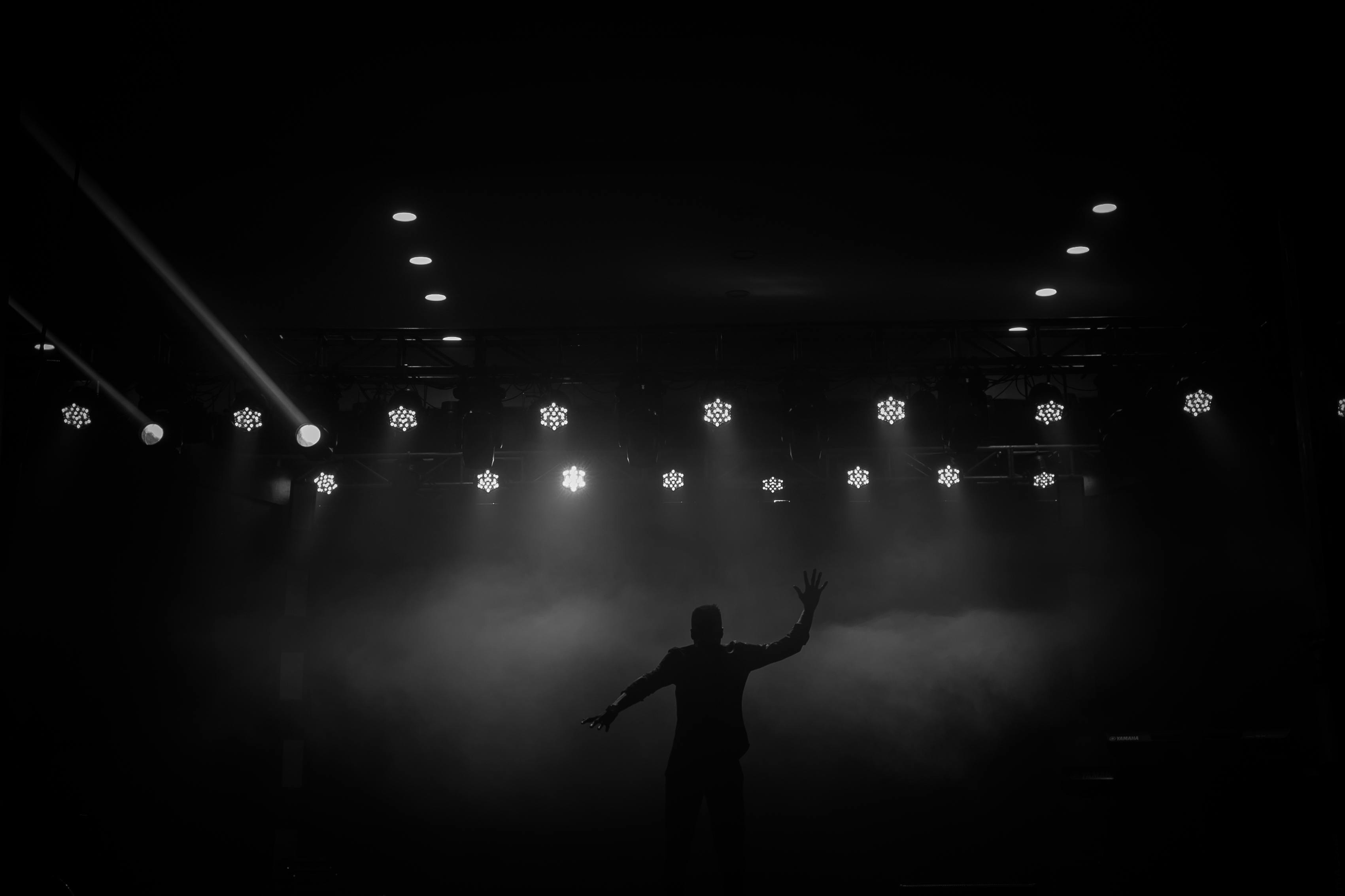 De franc Silueta d'un intèrpret sota les llums de l'escenari a Ibadan, Nigèria. Una escena dramàtica en blanc i negre. Foto d'estoc