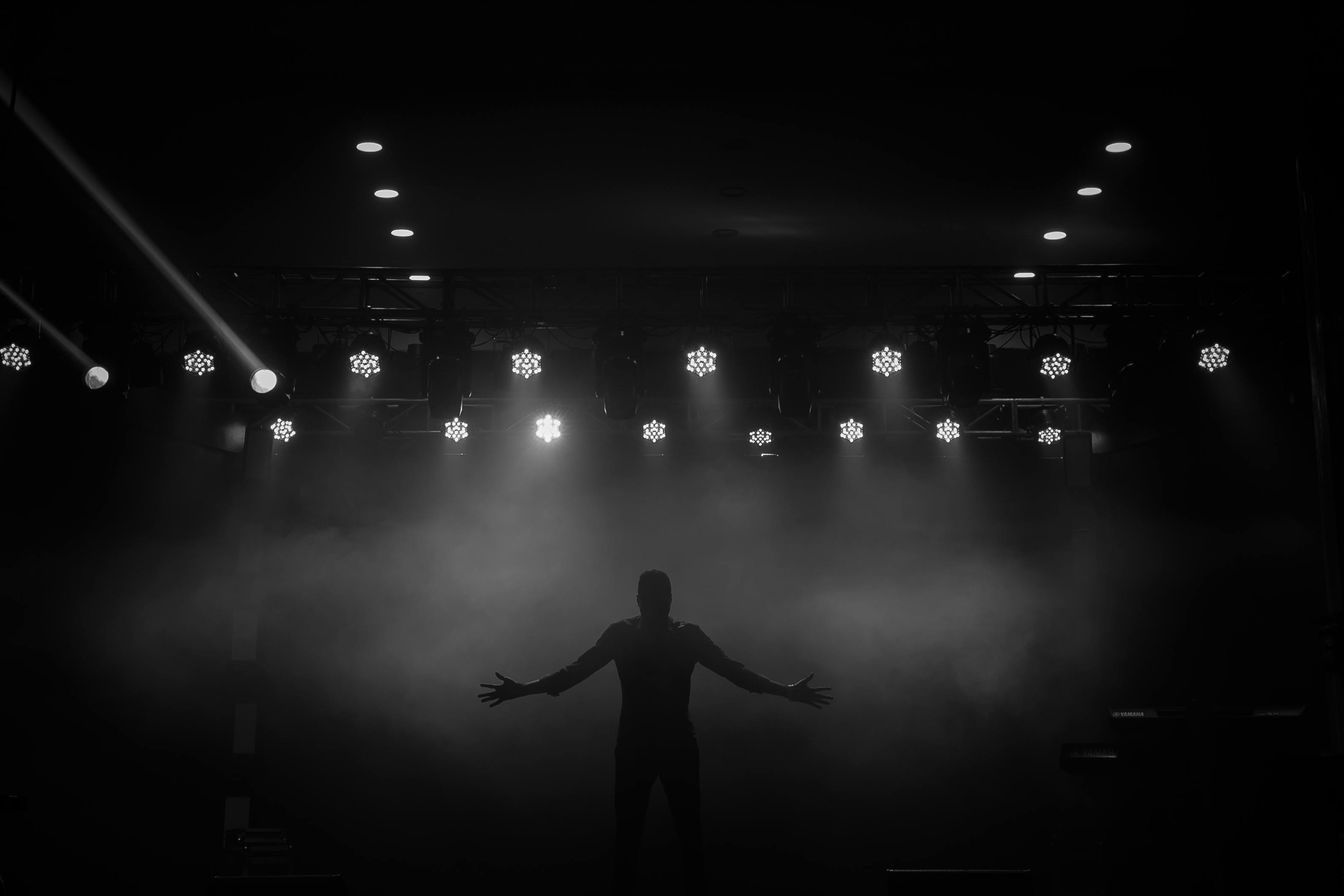 Gratuit Silhouette dramatique d'un artiste sur scène avec des lumières vives et du brouillard à Ibadan, au Nigéria. Photos