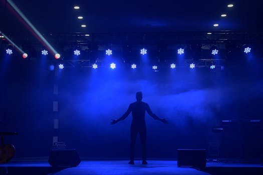 A dramatic scene of a silhouette standing on stage with vibrant blue lighting, offering great copyspace.