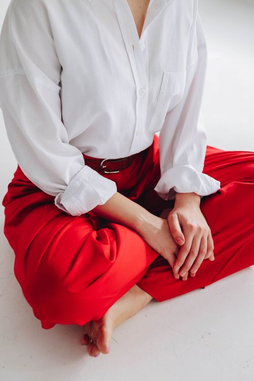 Free Stylish adult wearing a white shirt and red pants in a serene pose. Stock Photo