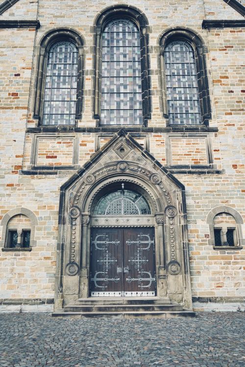 Free Stone facade of a historic church in Rheda-Wiedenbrück, featuring intricate door design and gothic windows. Stock Photo