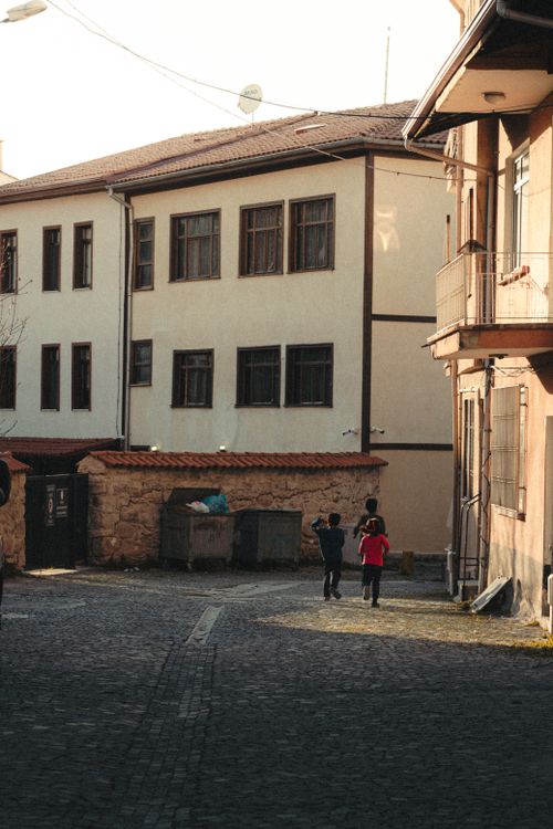 Free Two children playing in an old town street casting long shadows during sunset. Stock Photo