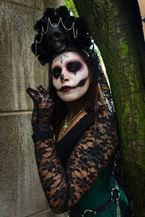 Free A woman in gothic attire and skeleton makeup posing outdoors against a tree. Stock Photo