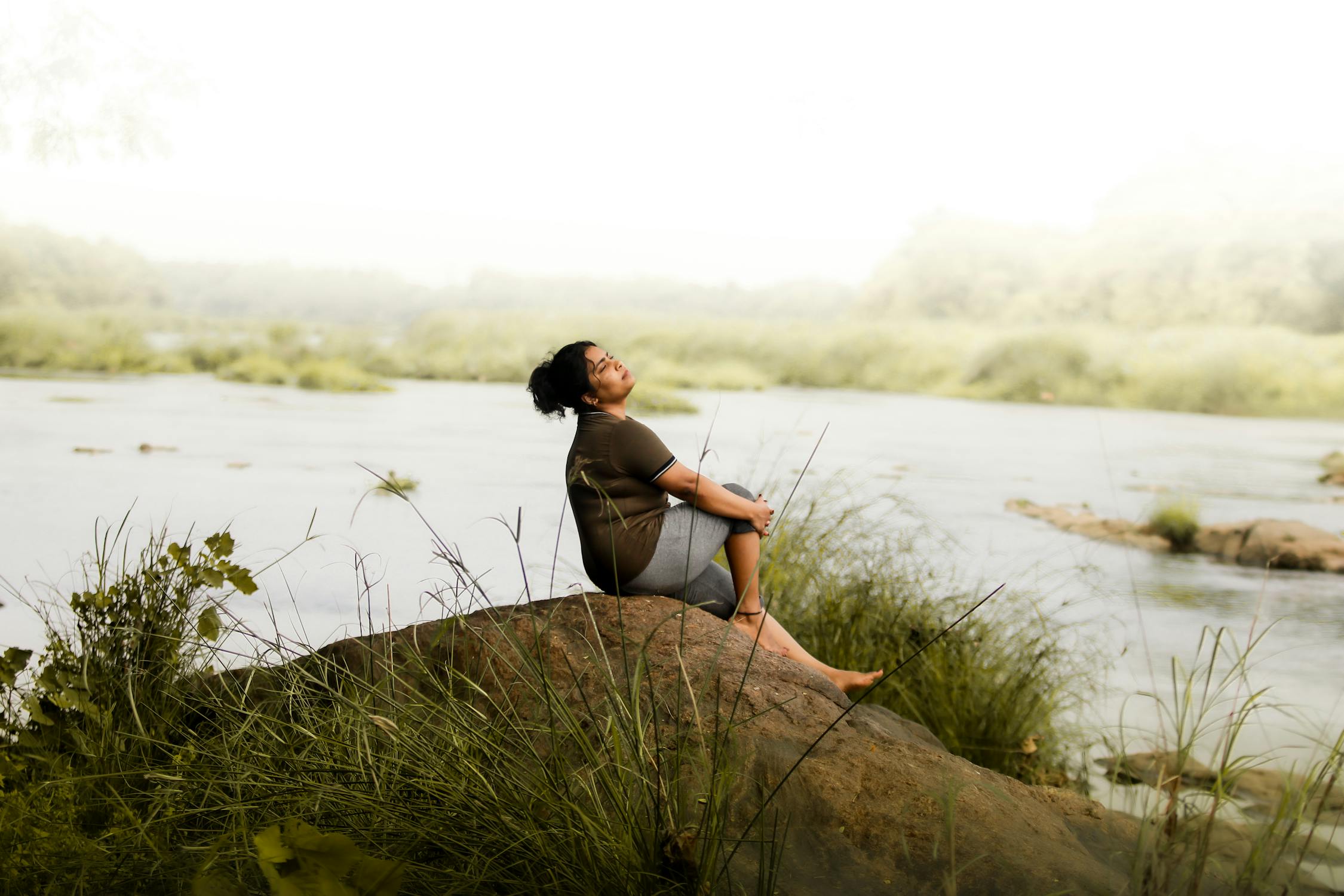 free photo of woman relaxing by riverbank in nature scene