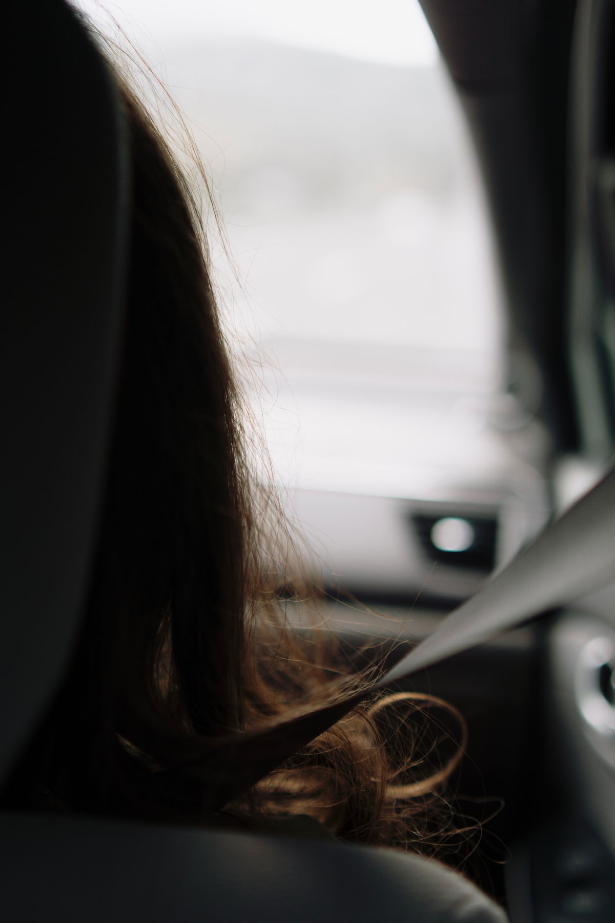 A passenger sitting comfortably in the back seat wearing a seatbelt