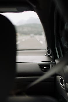 Rear passenger view looking through a car's windshield at an open road, capturing a sense of travel and adventure.