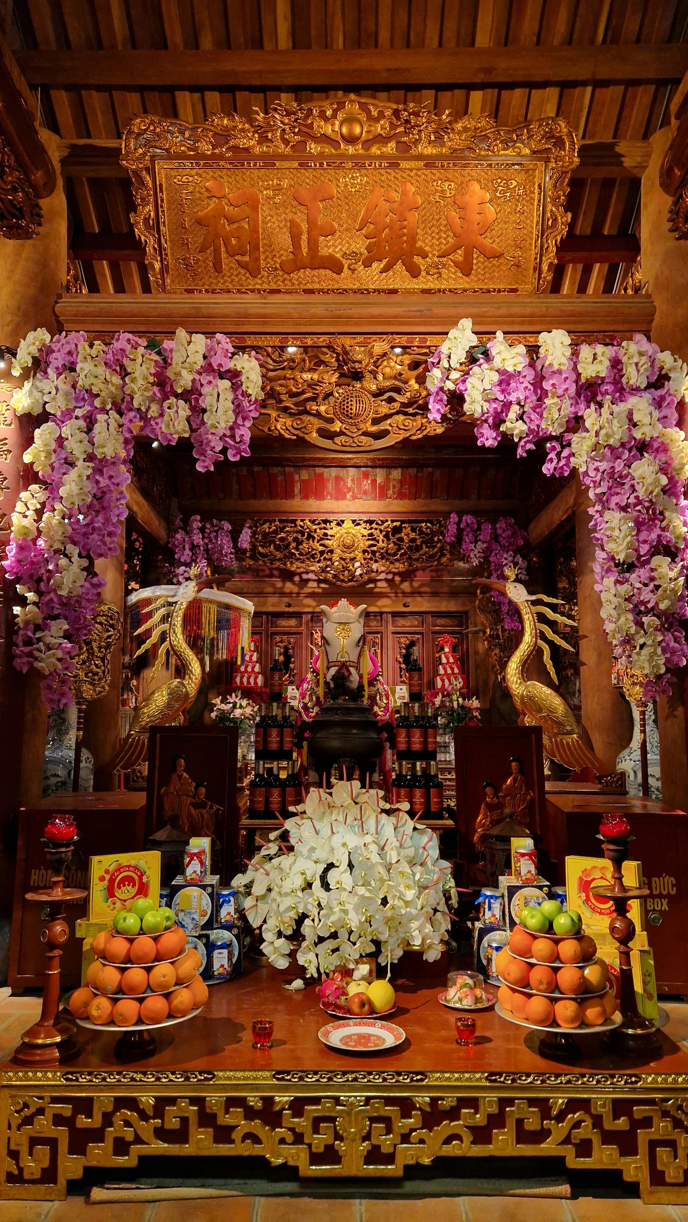 A richly decorated traditional Asian temple altar adorned with flowers and offerings.