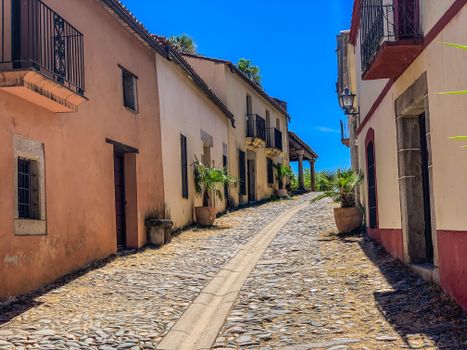 Quaint cobblestone street in a sunny Mediterranean village with colorful facades.
