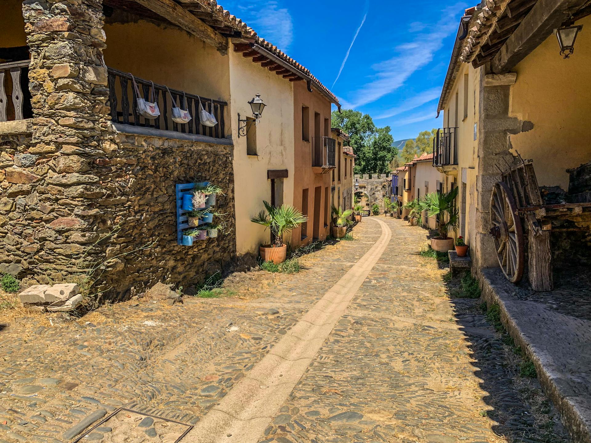 Rustic cobblestone street lined with charming village houses under a clear blue sky.