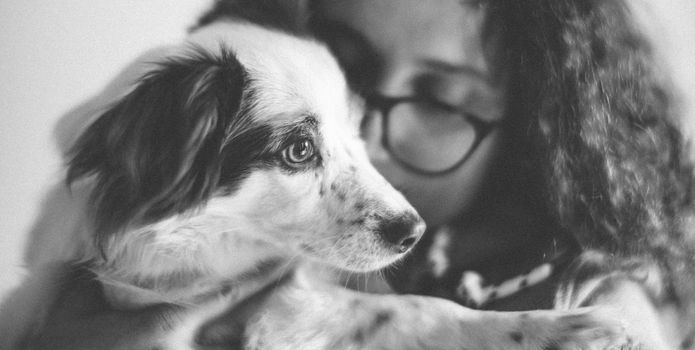 A touching black and white portrait of a girl lovingly hugging her dog.