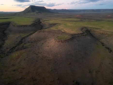 Explore the captivating aerial view of Namibia's vast landscape captured at sunset, showcasing unique geological formations.