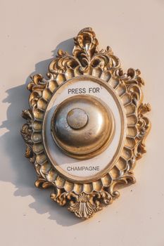 Ornate vintage doorbell with a golden frame labeled 'Press for Champagne' adds a touch of luxury.