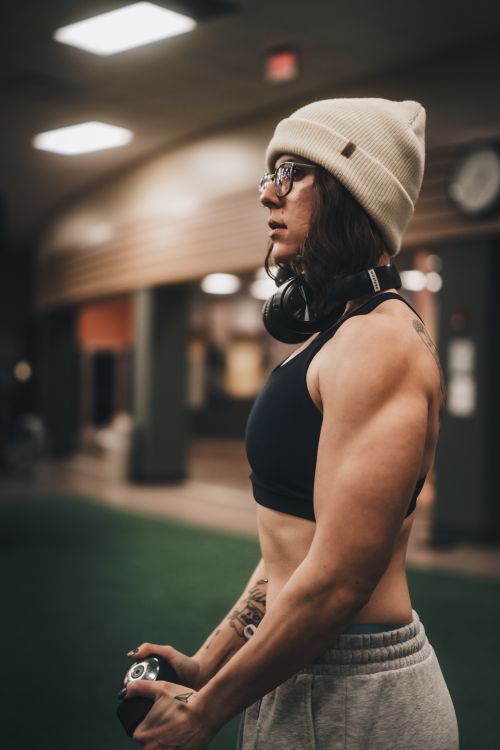 Free A determined female athlete in a gym, wearing a beanie and headphones, ready for a workout. Stock Photo