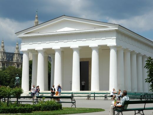 Captured in Burggarten, Vienna, this neoclassical temple stands against a vibrant city backdrop.