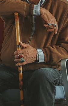 Close-up of an elderly man's hands adorned with rings, holding a cane in İstanbul.