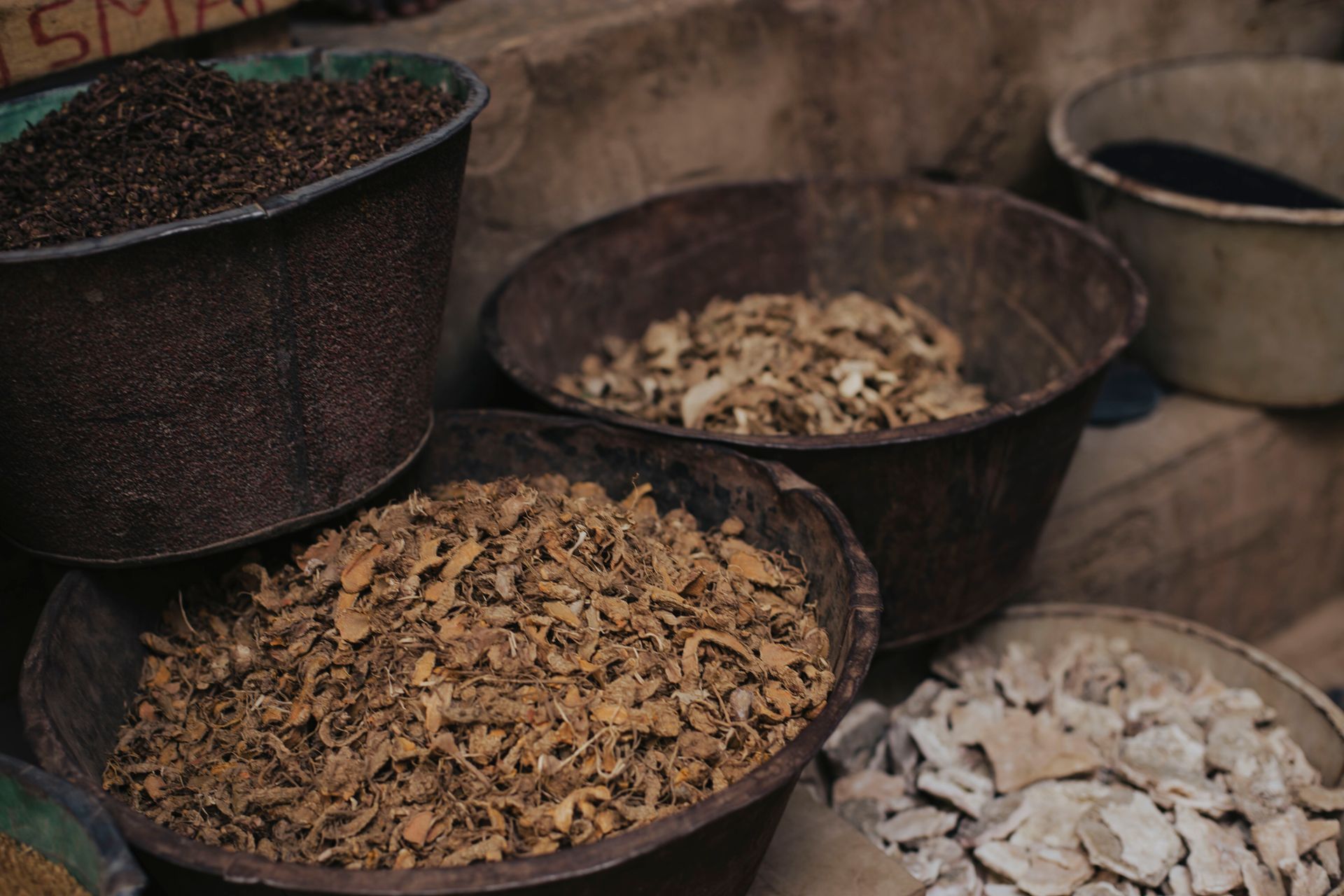 Baskets of assorted dried spices and herbs in a traditional market setting.