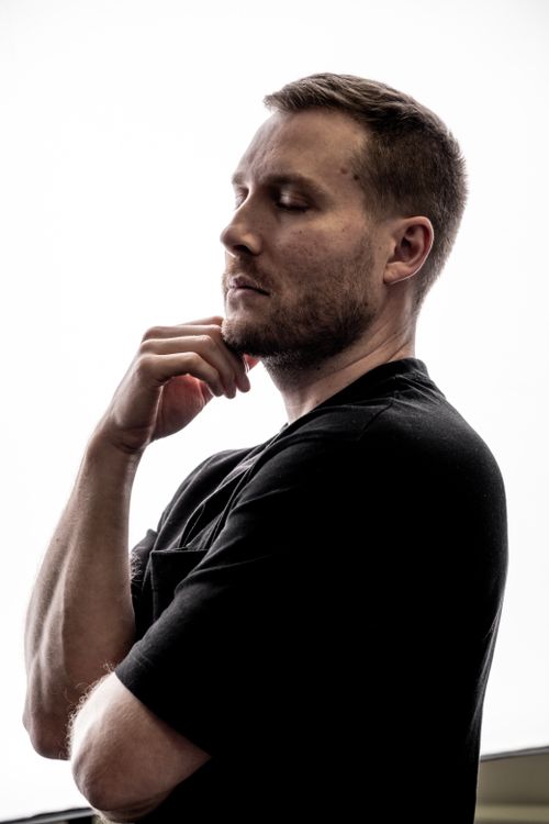 Free Contemplative adult male in black shirt, side view against bright background. Stock Photo