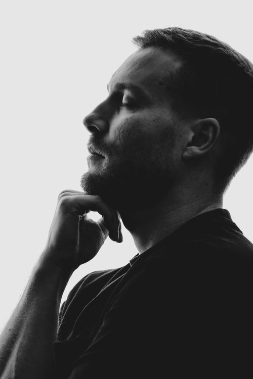 Free Black and white profile portrait of a thoughtful man with a hand on chin. Stock Photo