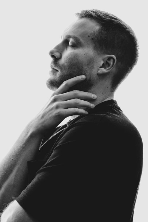 Free Black and white side portrait of a young man in thought, eyes closed, hand on chin. Stock Photo