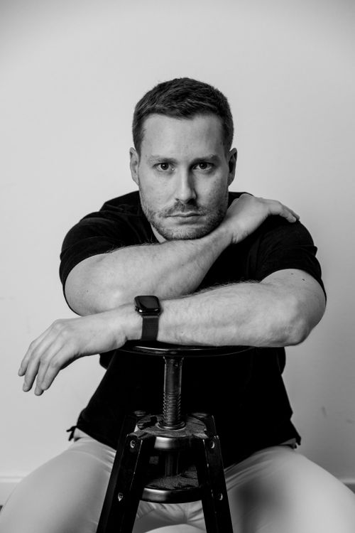 Free Black and white portrait of a man sitting pensively on a stool. Stock Photo