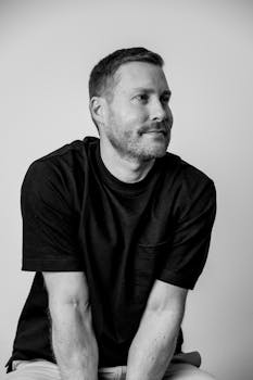 Black and white portrait of a relaxed man wearing a t-shirt, looking thoughtful.