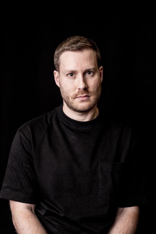 Free Studio portrait of a man wearing a black t-shirt, set against a dark background. Stock Photo