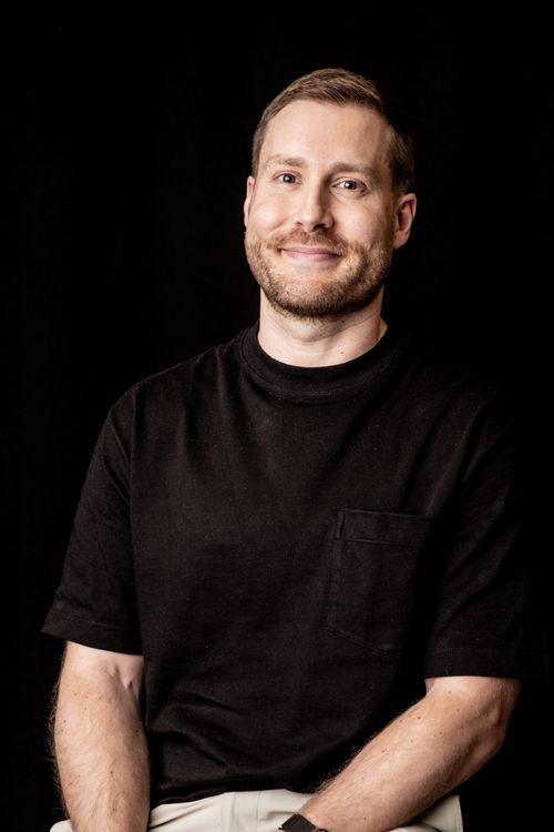 Free Cheerful man in black shirt smiles against a dark background. Stock Photo