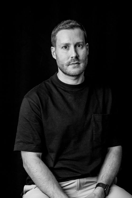 Free Monochrome portrait of a pensive man in casual attire against a dark background. Stock Photo