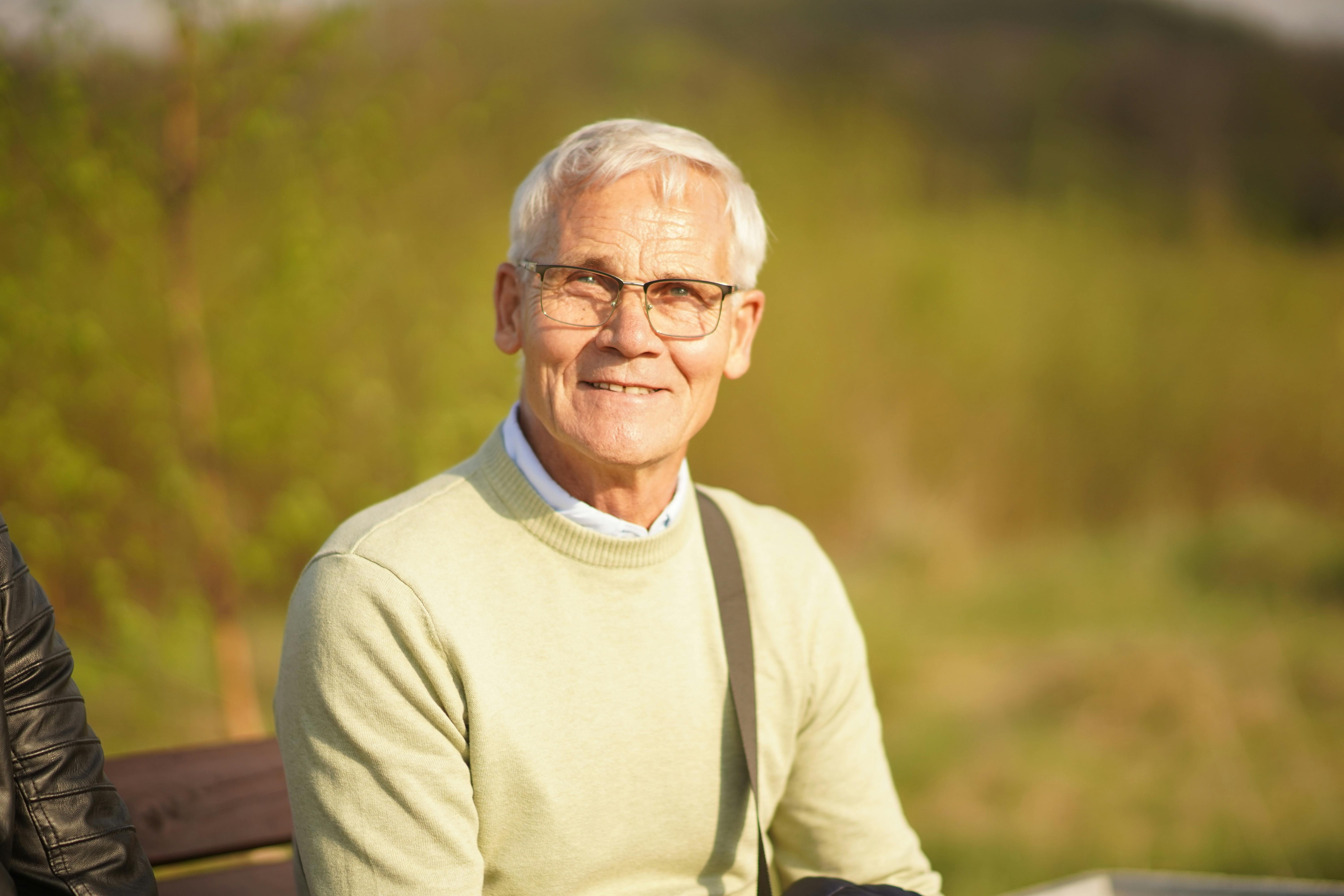 Elderly man smiling warmly in outdoor sunlight