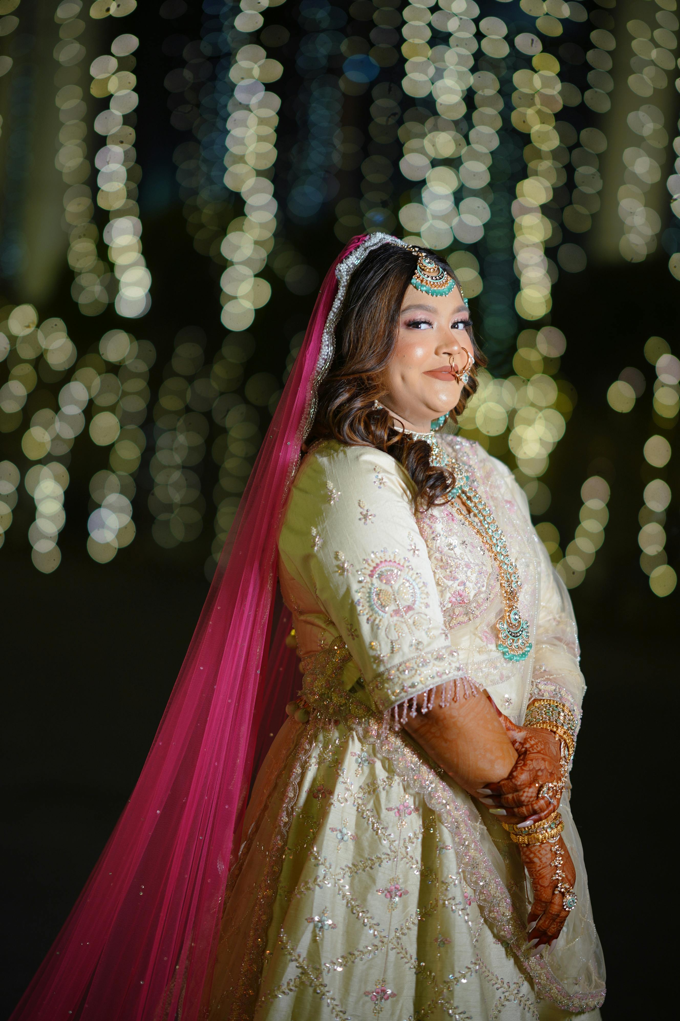 Beautiful portrait of a South Asian bride in traditional attire, illuminated by night lights.