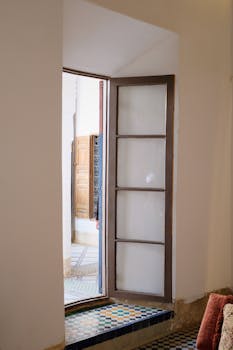 An open wooden door reveals a tiled interior, showcasing architectural details.