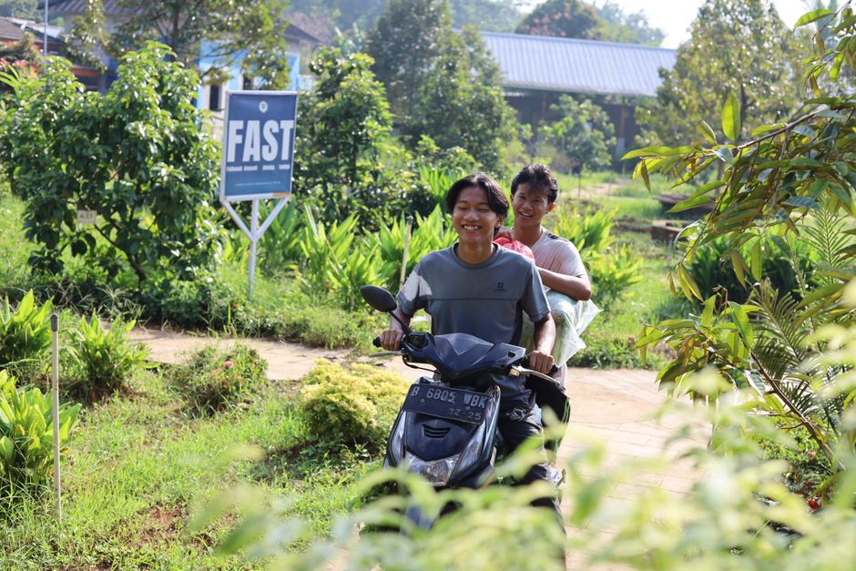 Fotomural Dos adolescentes alegres viajan en motocicleta a través de un exuberante paisaje verde bajo el sol de la mañana, disfrutando de su amistad.