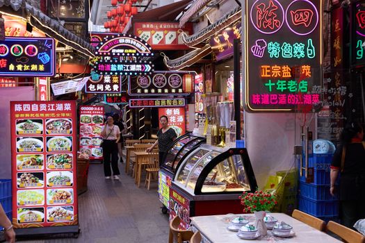 Explore a bustling night market with colorful neon signs and food vendors.