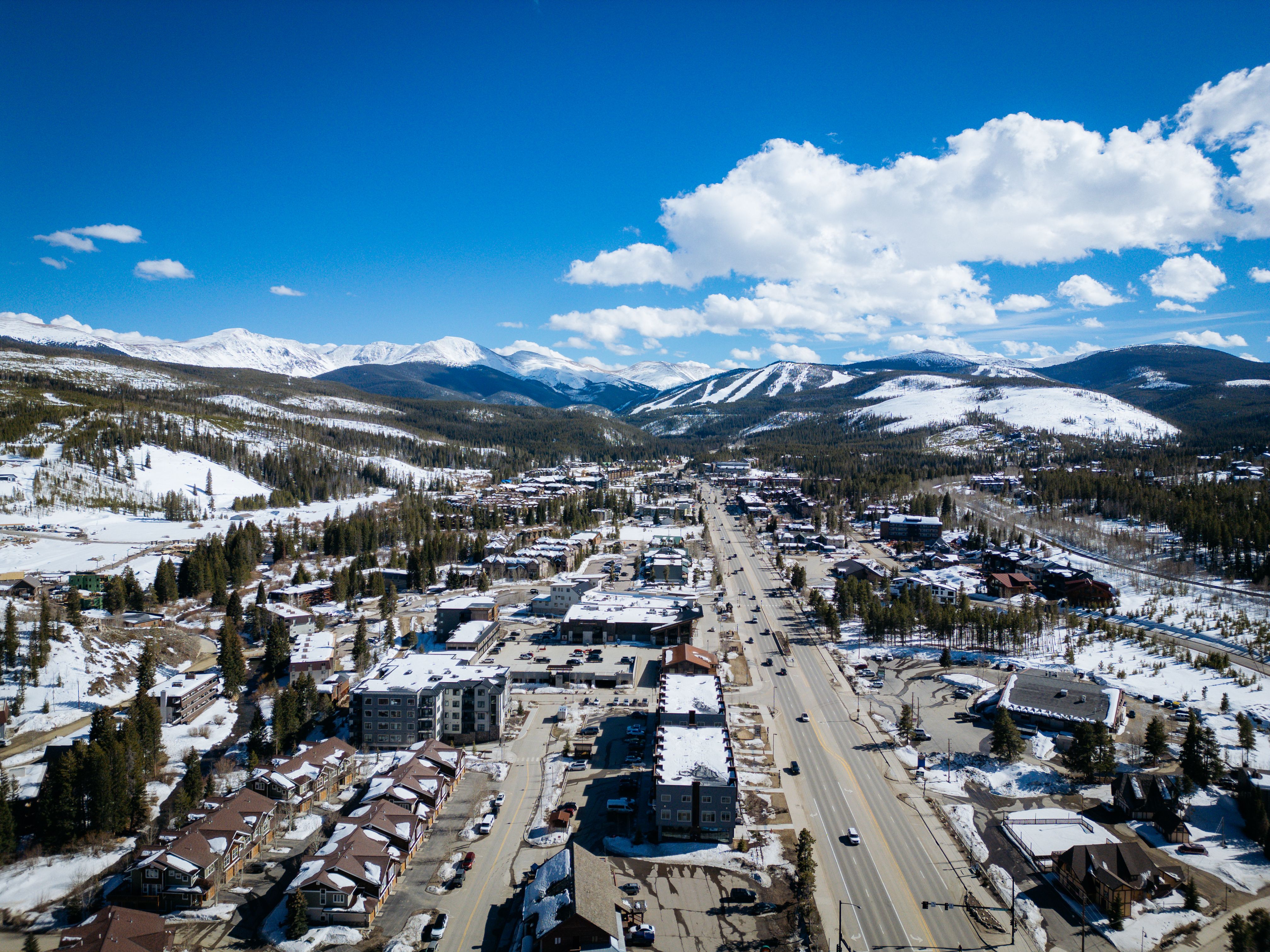 Aerial photo of a snow-covered town with distant mountains, taken in daylight.
