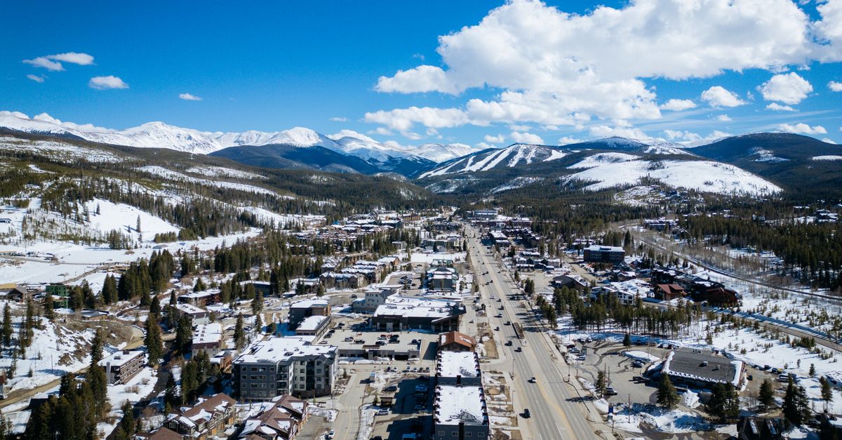 Aerial photo of a snow-covered town with distant mountains, taken in daylight.