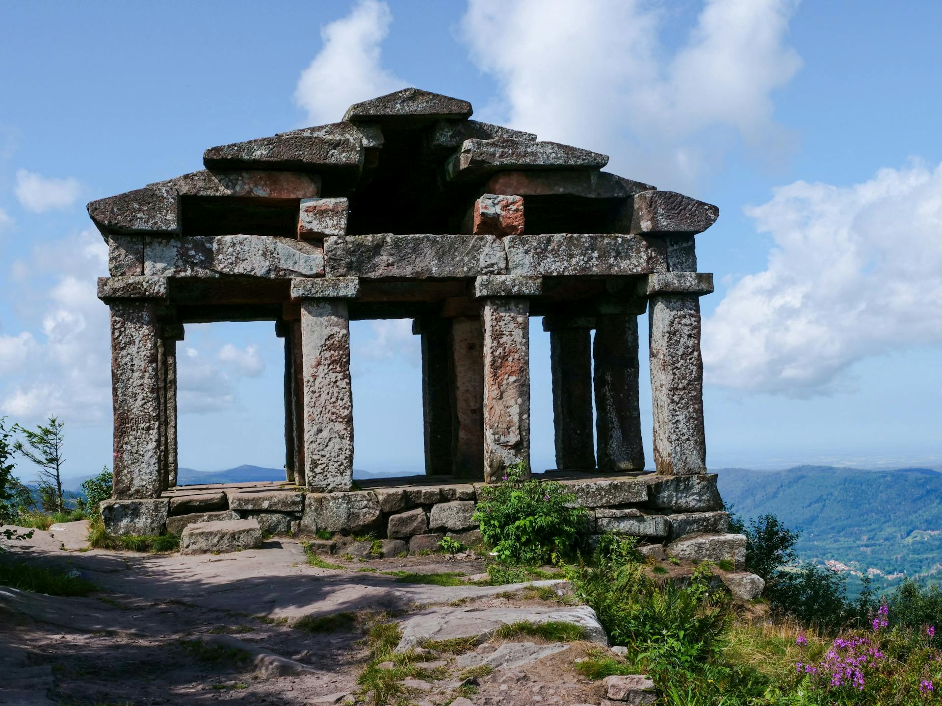 Explore the serene beauty of ancient stone temple ruins set against a lush mountain landscape.
