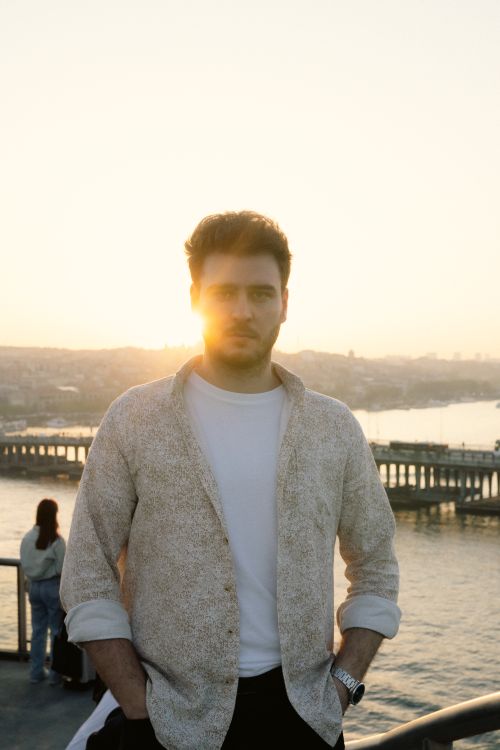 Free Man standing by the river at sunset with city skyline in the background. Stock Photo