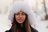 在特罗姆斯的北极景观中，一名戴着白色裘皮帽子的妇女站在冬天