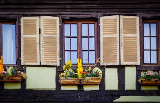Charming window display with shutters and floral decorations on a timber-framed building.