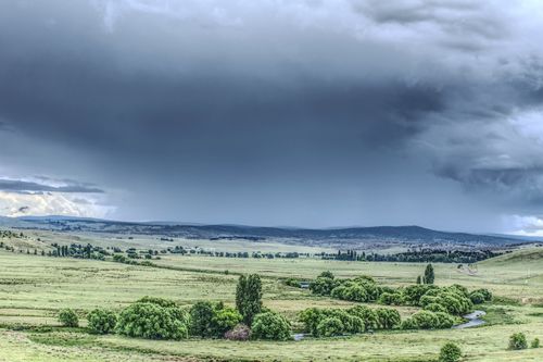 Free A stormy cloudscape hovering above a lush green pasture, evoking a dramatic and vibrant scene. Stock Photo