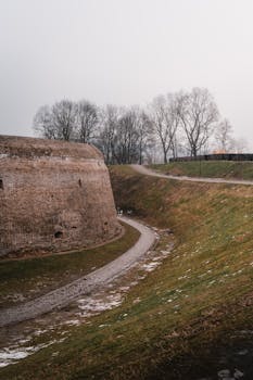 An ancient stone fort with a winding pathway surrounded by a serene winter landscape.