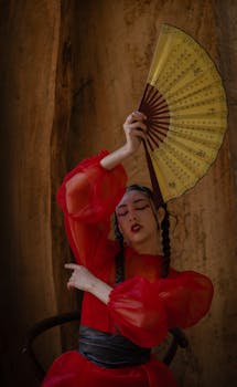 Artistic portrait of a woman in red dress holding a fan, showcasing elegance and cultural expression.