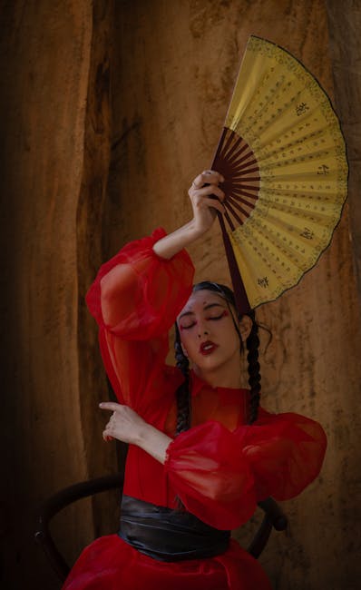 Artistic portrait of a woman in red dress holding a fan, showcasing elegance and cultural expression.