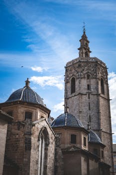 Stunning view of the gothic architecture of Valencia Cathedral's bell tower with a bright blue sky background.