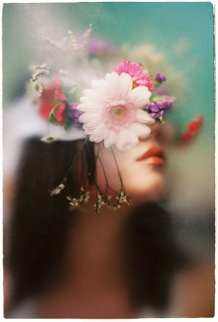 A dreamy portrait of a woman with a colorful floral mask, blending art and nature.
